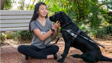 Black Lab sits in front of Asian teen
