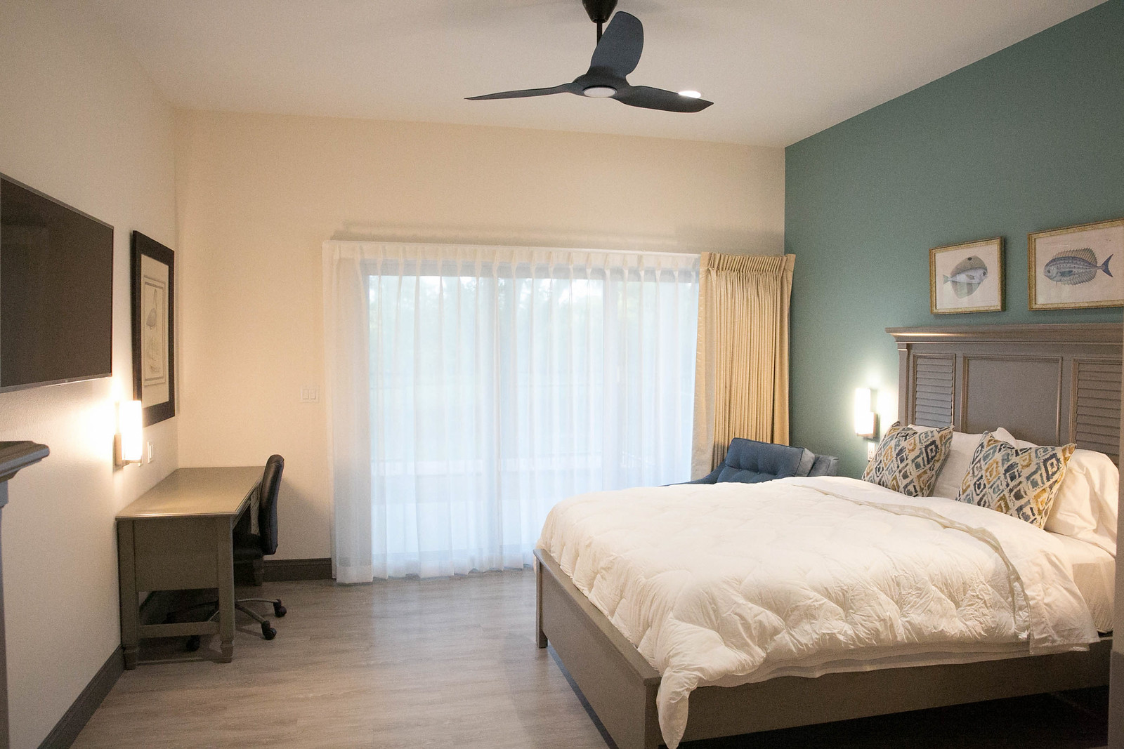 Room layout with a bed, chair, desk, tv, and decor