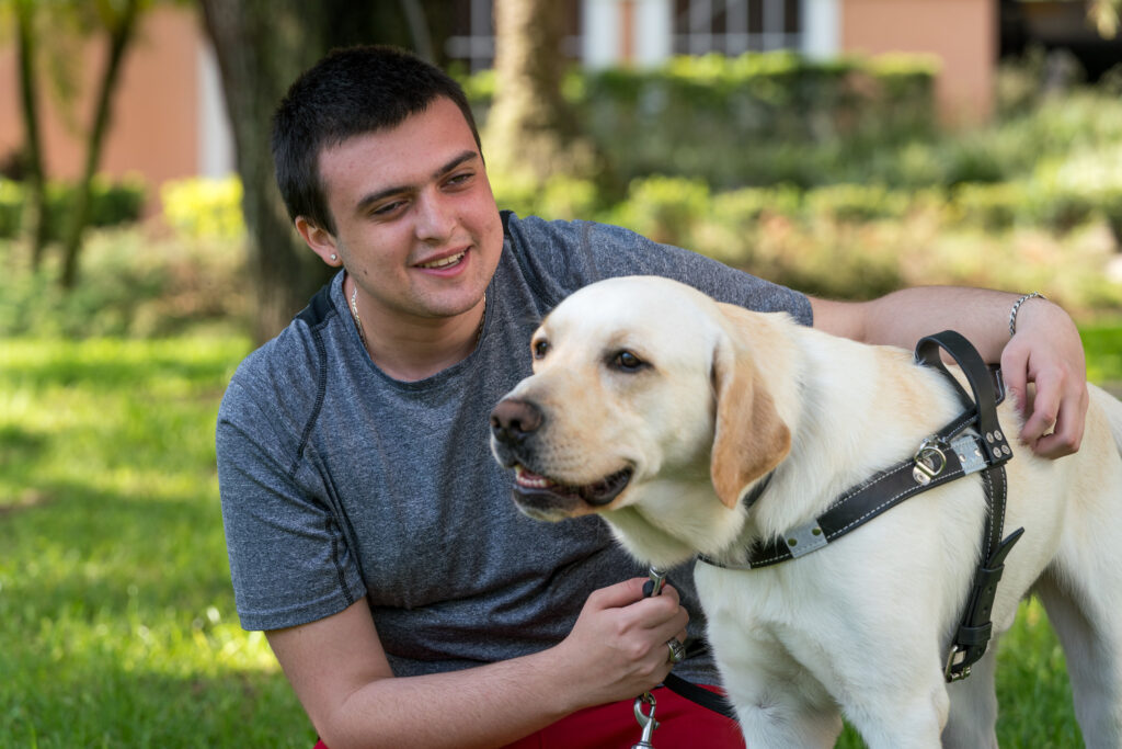 Man smiles while holding on to his guide dog