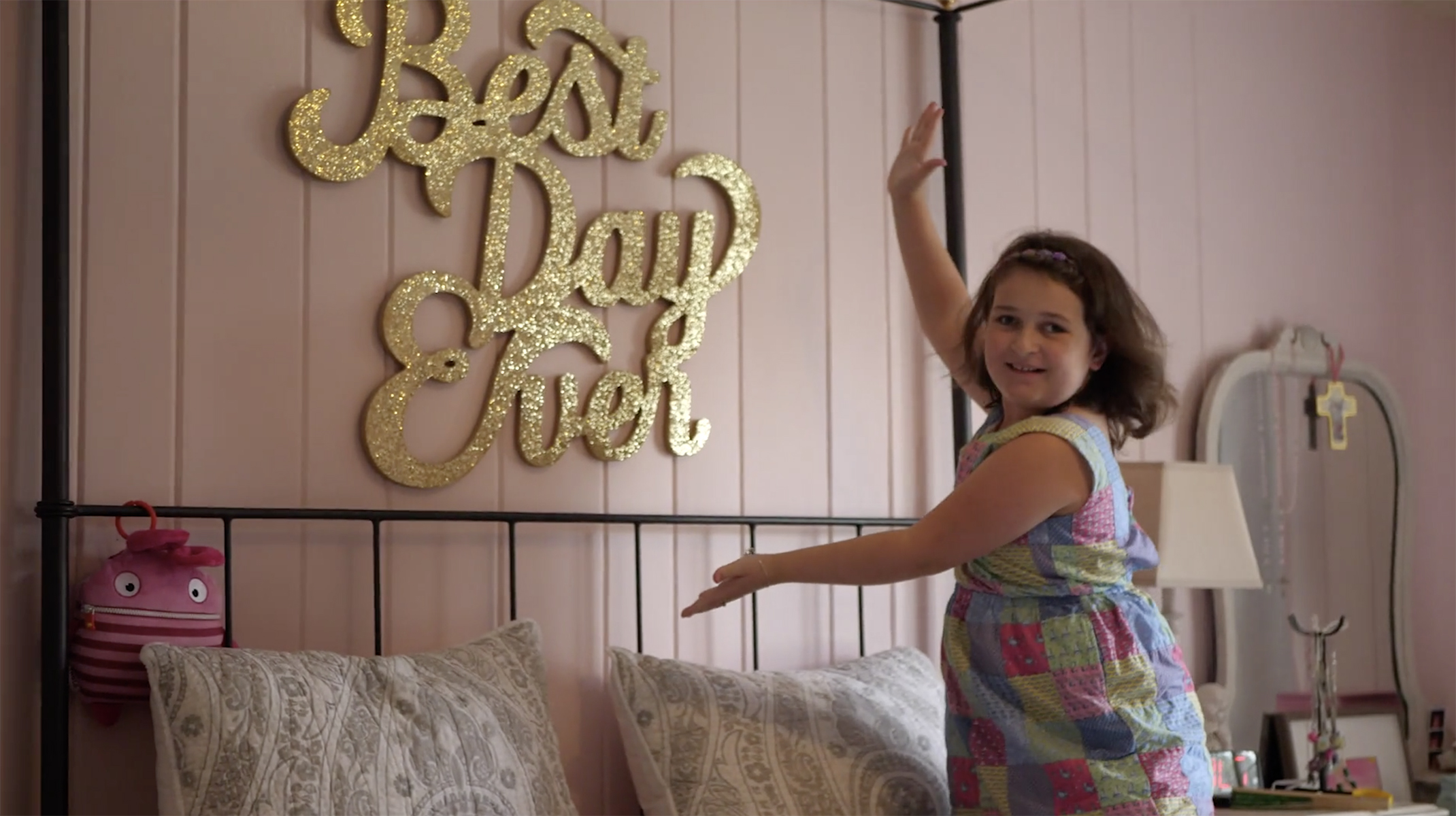 Young girl shows off her "Best Day Ever" sign in her room