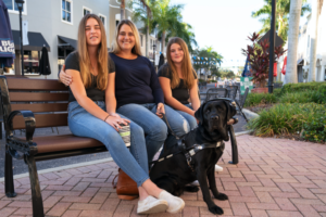Rachel sits with her two girls and her guide dog, Plum