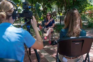 Camera woman faces camera at teen graduate