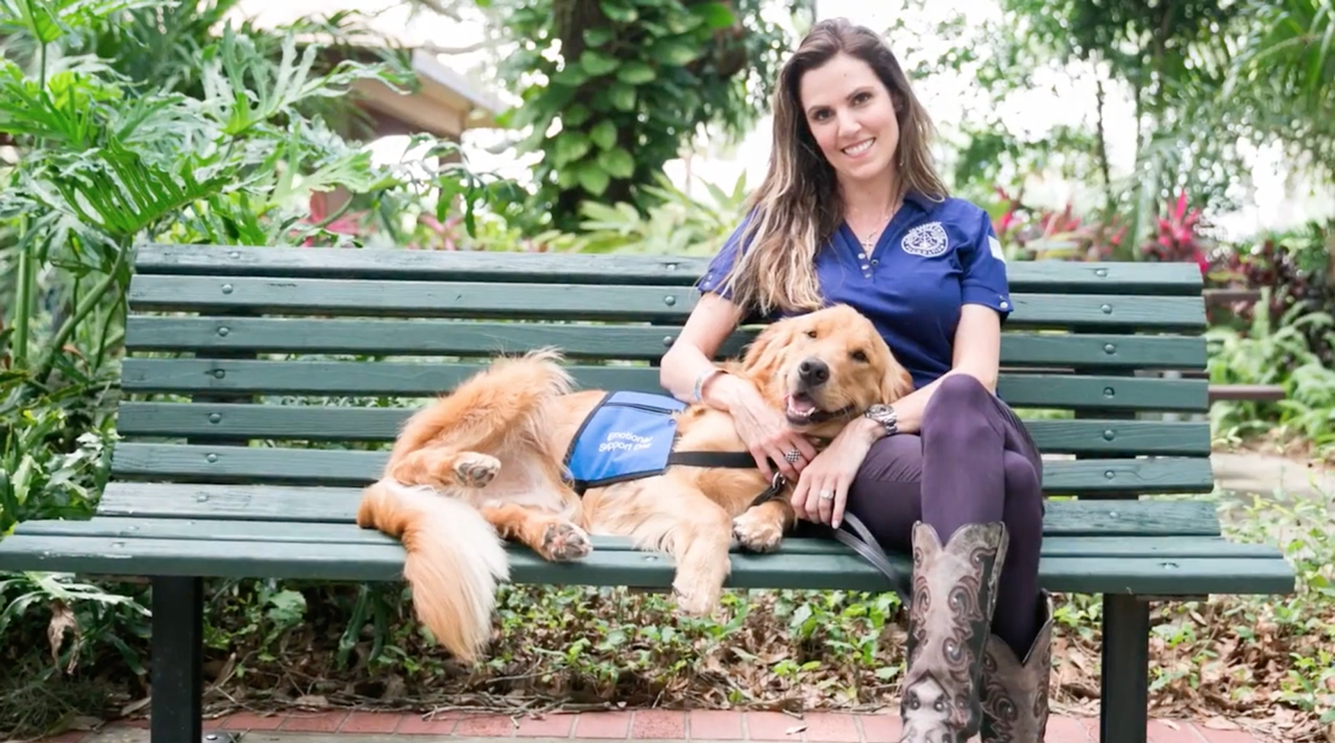 Woman sits on a bench with her service dog laying on her lap