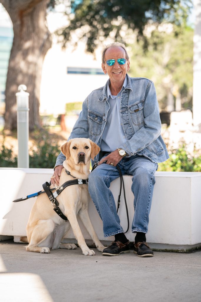 Bob poses with his guide dog sitting next to him