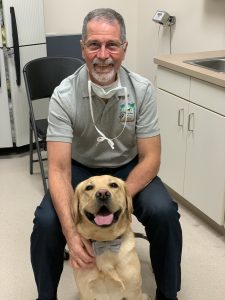 Dr. Tom Miller sits with a male yellow lab breeder