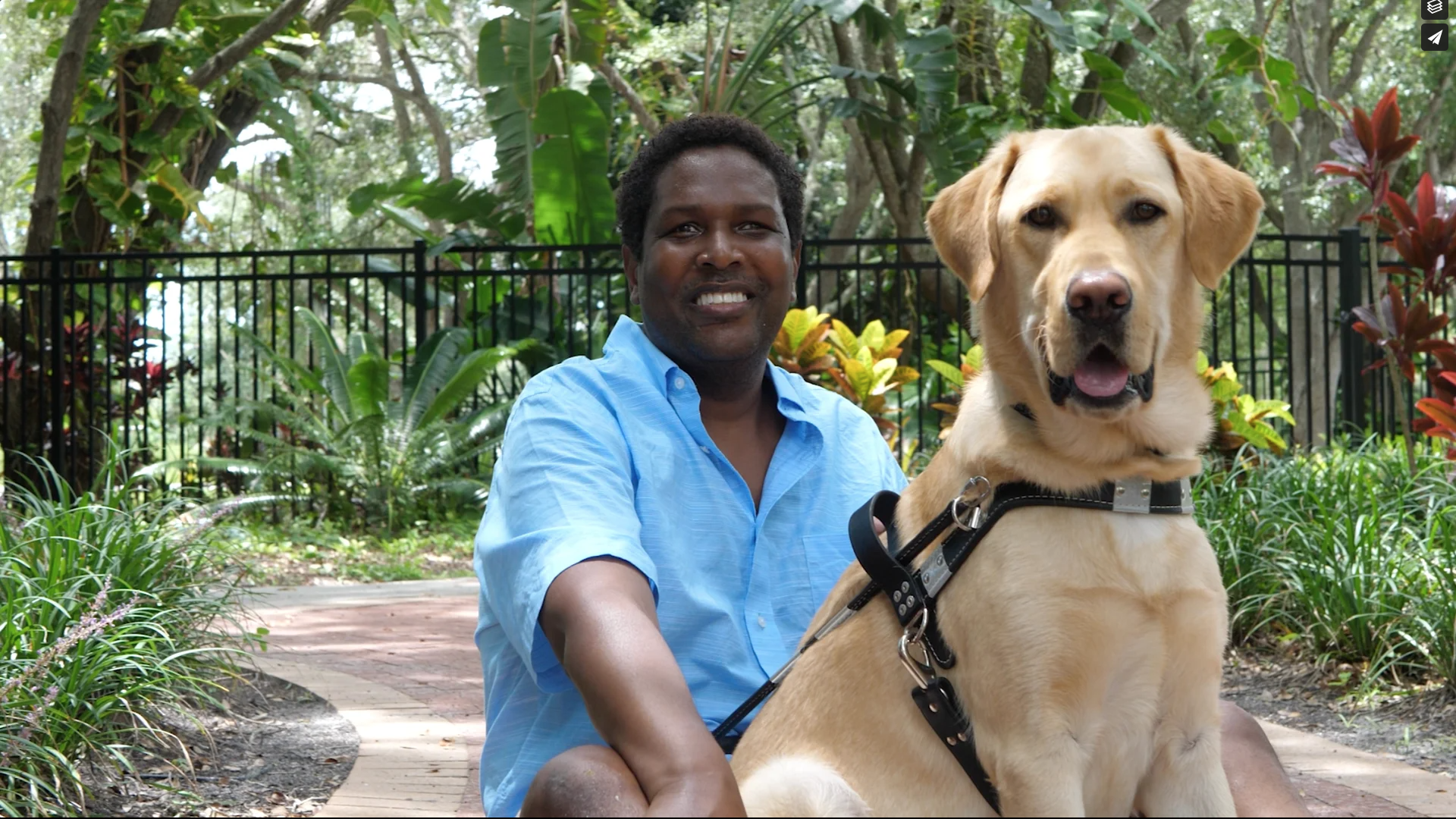 Man and yellow guide dog both look and smiles at the camera