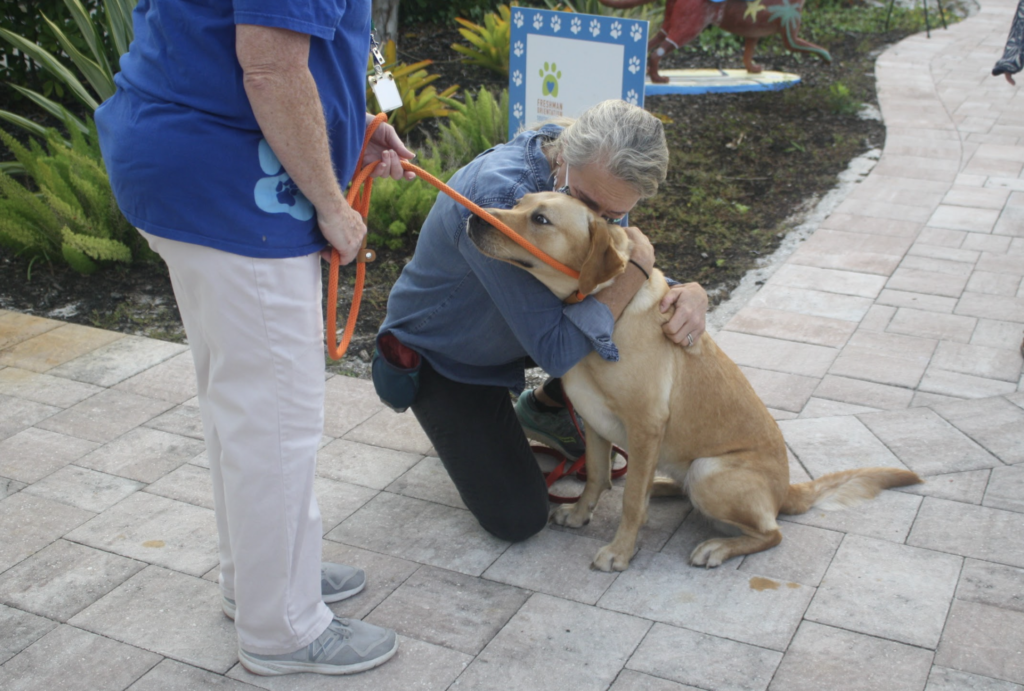 A puppy raiser cries as she gives her dog a final goodbye hug before a volunteer walks him away