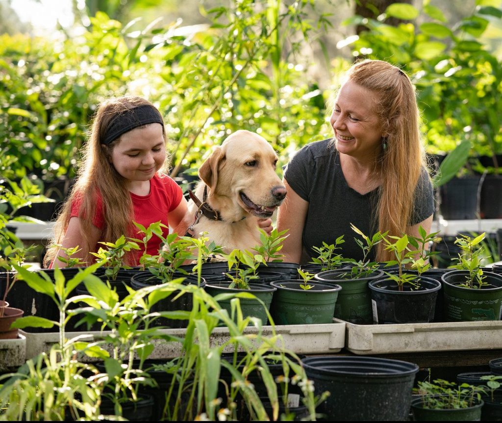 Girl and mom with yellow dog with potted plants
