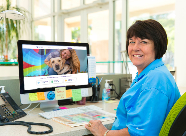 Older woman sits at desk and smiles at the camera