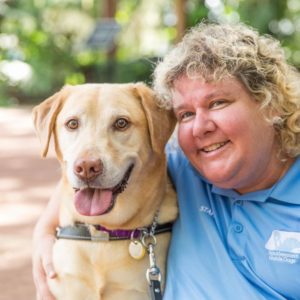Suzy Wilburn sitting next to a yellow Lab