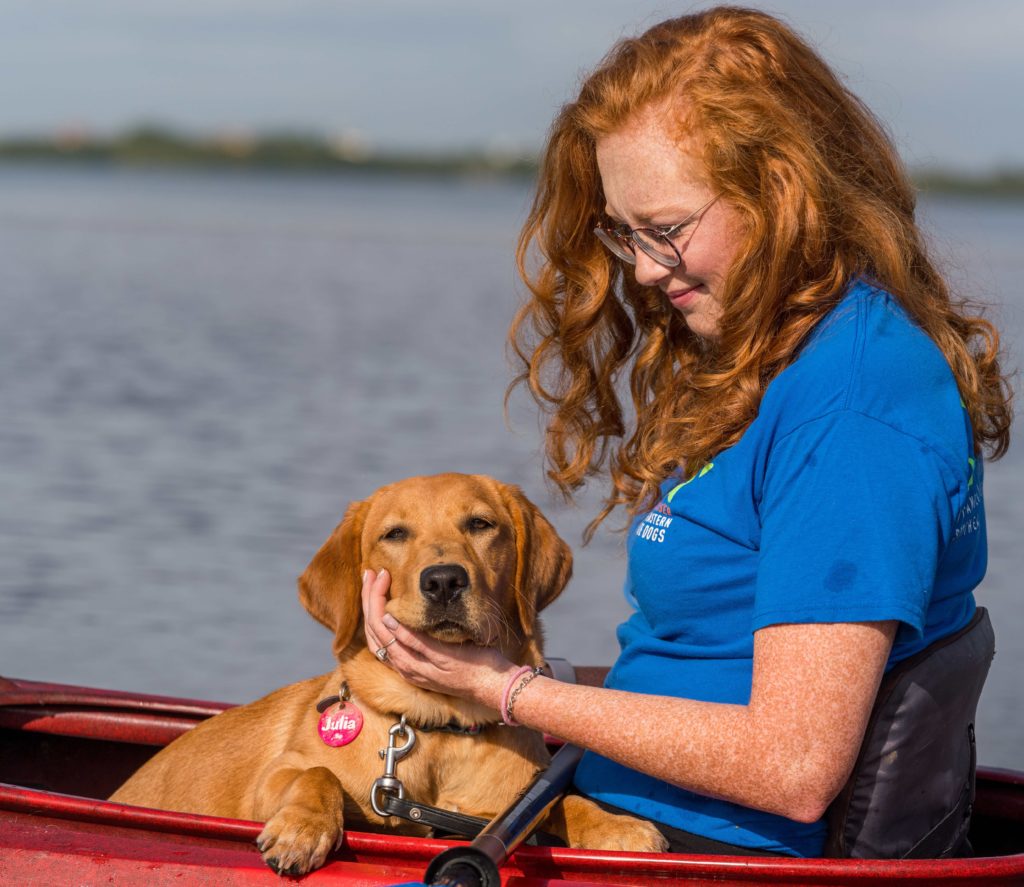 A photo of Meghan Watson and pup-in-training Julia sitting together in a kayak in the water.
