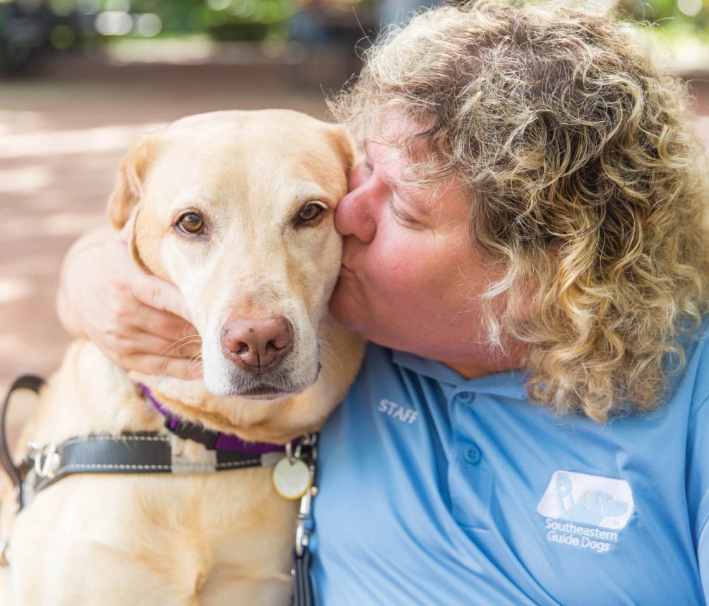 A photo of Suzy Wilburn kissing her guide dog Carson.