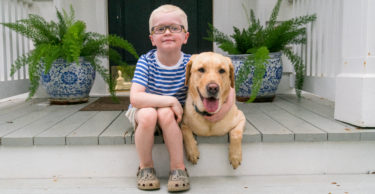 James and Kid's Companion Dog Cherman sitting together on a front porch.